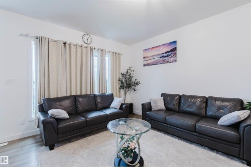 Recessed windows with curtain rods, light wood-finish flooring, and crisp white walls - 104 Meadowview Way, Leduc, AB - Indoor Photo Showing Living Room
