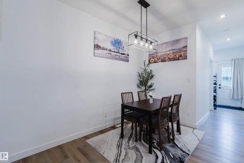 Open-concept dining area featuring wood-finish flooring, recessed lighting, and a contemporary linear chandelier - 104 Meadowview Way, Leduc, AB - Indoor Photo Showing Dining Room