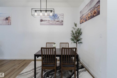 Wood-finish flooring with a rectangular area rug - 104 Meadowview Way, Leduc, AB - Indoor Photo Showing Dining Room