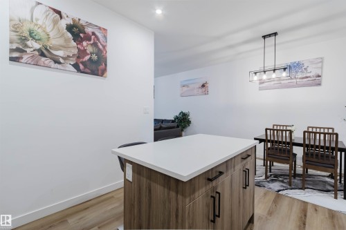 Central kitchen island with a light-toned countertop, wood-finish cabinetry, and black hardware - 104 Meadowview Way, Leduc, AB - Indoor
