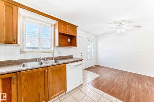 Kitchen with wood-finish cabinetry, a double basin stainless steel sink, and a white tile backsplash - 11727 83 Street Nw, Edmonton, AB - Indoor Photo Showing Kitchen With Double Sink