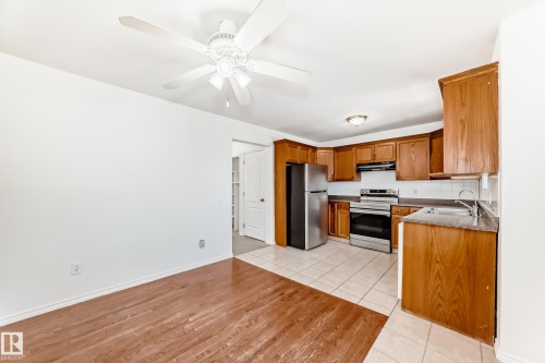 Kitchen with wood cabinetry, stainless steel appliances, and a tiled floor - 11727 83 Street Nw, Edmonton, AB - Indoor Photo Showing Kitchen
