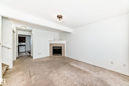 Fireplace with tile surround and mantel, flush-mount ceiling light fixture, and white painted walls - 11727 83 Street Nw, Edmonton, AB - Indoor Photo Showing Living Room With Fireplace