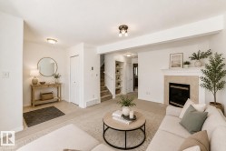 Virtually staged room with illustrating potential of room with furniture, decor and new flooring show a recessed fireplace with hearth, built-in shelving, carpeted staircase, and tiled entry - 