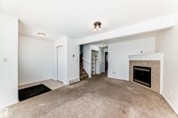 Living area with a tiled fireplace, mantel, built-in shelving, and carpeting - 