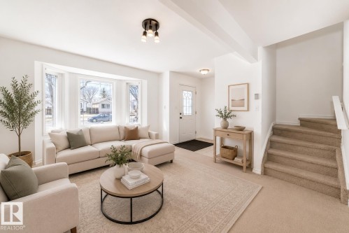 Virtually staged room with illustrating potential of room with furniture, decor and new flooring show a bright living room with a bay window, recessed lighting, and a front entry door with decorative glass - 11727 83 Street Nw, Edmonton, AB - Indoor Photo Showing Living Room