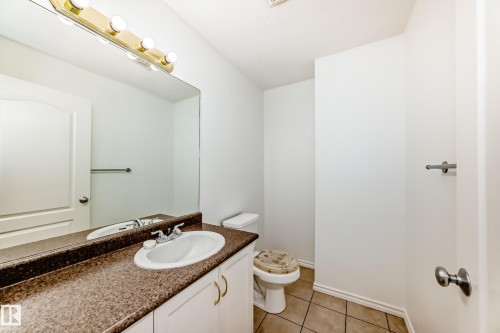Integrated vanity with a white basin and speckled countertop, full-width mirror, and a four-bulb light fixture - 11727 83 Street Nw, Edmonton, AB - Indoor Photo Showing Bathroom