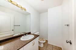 Integrated vanity with a white basin and speckled countertop, full-width mirror, and a four-bulb light fixture - 