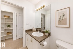 Vanity with a built-in sink and dark countertop, large wall-mounted mirror, and overhead vanity lighting - 