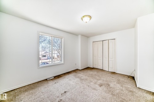 Recessed window with security bars, bi-fold closet doors, wall-mounted ceiling light fixture - 11727 83 Street Nw, Edmonton, AB - Indoor Photo Showing Other Room