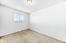 Carpeted room with a flush-mount ceiling light fixture, white walls, and a window with white trim - 