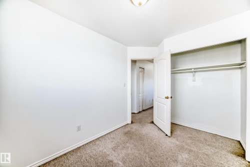 Neutral wall paint, textured carpeting, interior door with gold-tone hardware, built-in closet shelving, and a ceiling-mounted light fixture - 11727 83 Street Nw, Edmonton, AB - Indoor Photo Showing Other Room