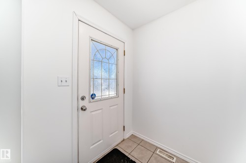 White door with an arched decorative glass insert and transom, tile flooring, and neutral wall tones - 11727 83 Street Nw, Edmonton, AB - Indoor Photo Showing Other Room