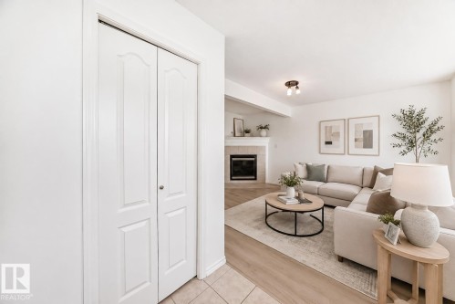 Virtually staged room with illustrating potential of room with furniture, decor and new flooring show a bright, open-concept living area featuring a wood-finish plank floor, neutral paint throughout, and abundant natural light - 11727 83 Street Nw, Edmonton, AB - Indoor Photo Showing Living Room With Fireplace
