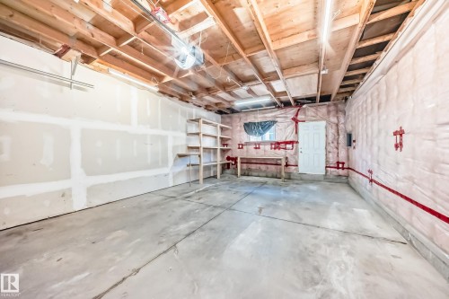 Unfinished garage space featuring a concrete floor, exposed wood ceiling joists, and built-in shelving - 11727 83 Street Nw, Edmonton, AB - Indoor Photo Showing Garage