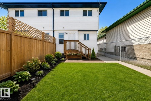 Virtually enhanced image of expansive green lawn with a landscaped garden bed, wood privacy fence, and a raised wood deck with stairs - 11727 83 Street Nw, Edmonton, AB - Outdoor With Exterior