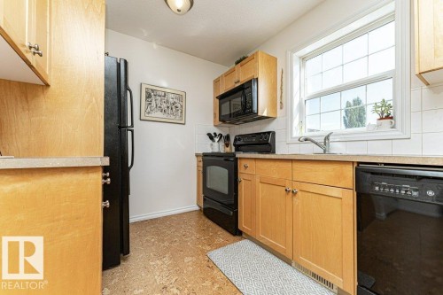 Kitchen featuring light wood-finish cabinetry, black appliances, white tile backsplash, and a window with grid pattern - 1539 Kinross Road Nw, Edmonton, AB - Indoor Photo Showing Kitchen