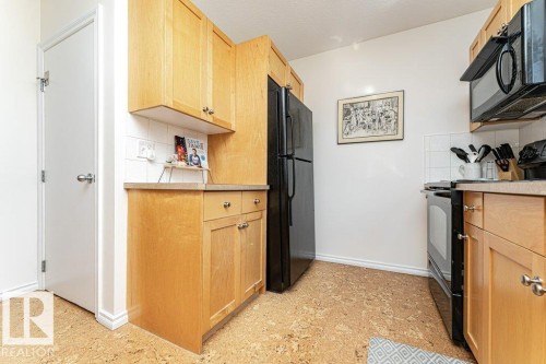 Light wood cabinetry with silver-tone hardware, white tile backsplash, black appliances, and textured flooring - 1539 Kinross Road Nw, Edmonton, AB - Indoor Photo Showing Kitchen