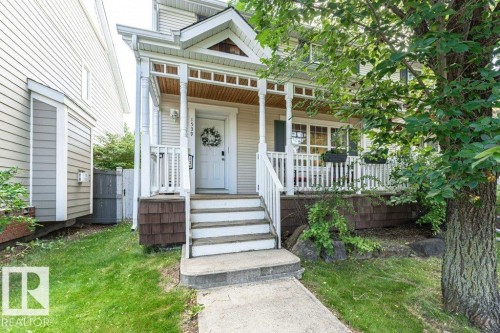 Covered front porch with white railings and columns, shingle siding, and a mature front yard tree - 1539 Kinross Road Nw, Edmonton, AB - Outdoor With Deck Patio Veranda With Facade