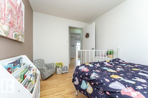 Smooth wall finish with a neutral color palette, wood-finish flooring, and a white door with a circular handle - 1539 Kinross Road Nw, Edmonton, AB - Indoor Photo Showing Bedroom