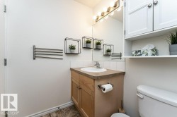 Bathroom featuring a wood-finish vanity with an integrated sink, a wall-mounted mirror, and overhead vanity lighting - 