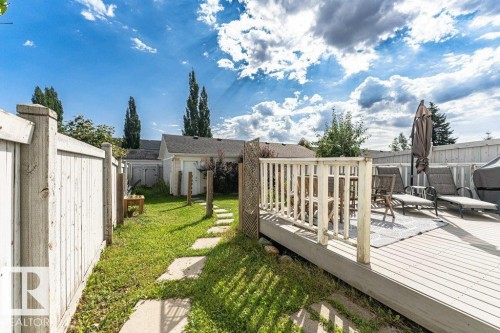Expansive backyard featuring a wood deck, wood privacy fencing, a concrete paver pathway, and a grass lawn - 1539 Kinross Road Nw, Edmonton, AB - Outdoor