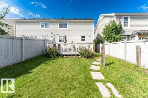 Expansive grassy yard area featuring a concrete paver pathway, wood fencing, and a raised wood deck - 1539 Kinross Road Nw, Edmonton, AB - Outdoor With Deck Patio Veranda