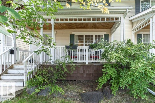 Inviting front porch with white railings and columns, featuring a beadboard ceiling and transom windows - 1539 Kinross Road Nw, Edmonton, AB - Outdoor With Deck Patio Veranda