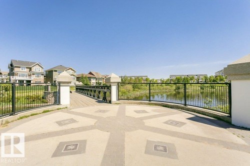 Paved outdoor area with decorative inlay, surrounded by a black metal fence and stone pillars - 1539 Kinross Road Nw, Edmonton, AB - Outdoor