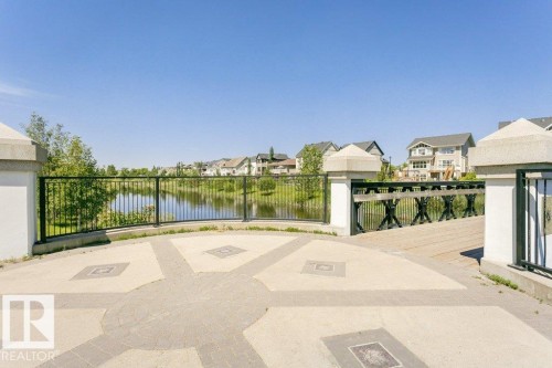 Paved patio with decorative inlay, black metal railing, and a wooden pedestrian bridge over a water feature - 1539 Kinross Road Nw, Edmonton, AB - Outdoor