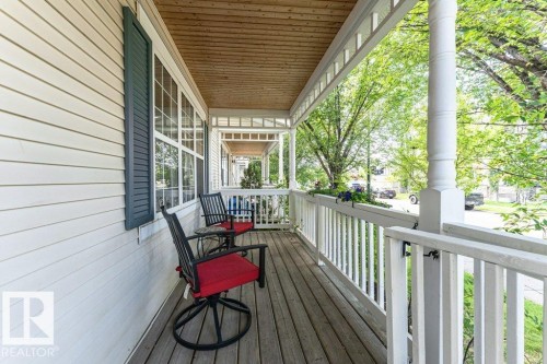 Expansive front porch featuring wood-finish flooring, white siding, and decorative shutters - 1539 Kinross Road Nw, Edmonton, AB - Outdoor With Deck Patio Veranda With Exterior