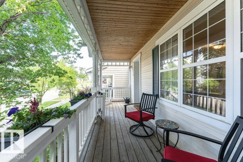 Expansive front porch featuring a wood-finish ceiling, durable decking, white railings, and large windows with grilles - 1539 Kinross Road Nw, Edmonton, AB - Outdoor With Deck Patio Veranda With Exterior