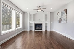 Hardwood flooring, built-in shelving, fireplace, ceiling fan with integrated lighting, and recessed lighting - 