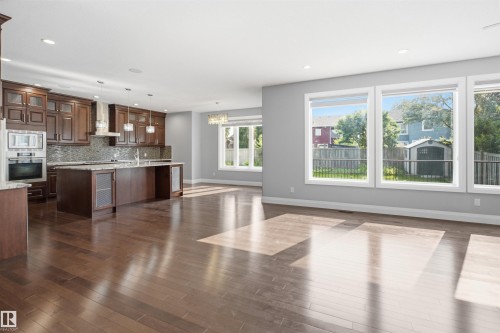 Open-concept living space featuring wood-finish flooring, a kitchen with dark wood cabinetry, stainless steel appliances, a center island, and recessed lighting - 427 Windermere Road Nw, Edmonton, AB - Indoor Photo Showing Kitchen