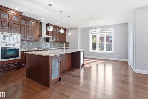 Kitchen with wood-finish flooring, dark wood cabinetry, granite countertops, and stainless steel appliances - 427 Windermere Road Nw, Edmonton, AB - Indoor Photo Showing Kitchen With Upgraded Kitchen