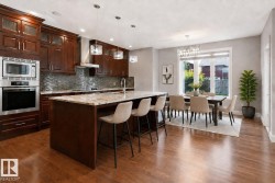 Gourmet kitchen with rich wood cabinetry, stainless steel appliances, a center island with a stone countertop, and wood-finish flooring - 
