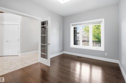 Dark wood-finish flooring, light grey painted walls, white trim, and a large window with a black metal railing - 