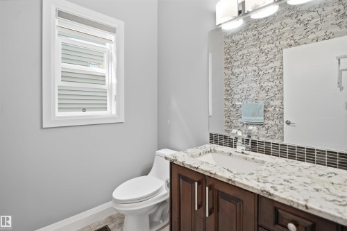 Dark wood-finish vanity with an integrated sink, white patterned countertop, and chrome faucet - 427 Windermere Road Nw, Edmonton, AB - Indoor Photo Showing Bathroom