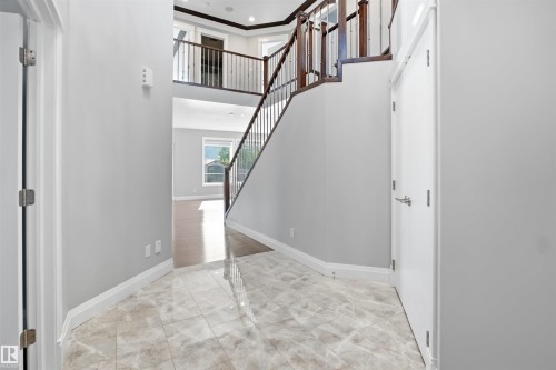 Two-story entryway with tile flooring, wood-finish staircase with wrought iron balusters, and recessed lighting - 427 Windermere Road Nw, Edmonton, AB - Indoor Photo Showing Other Room
