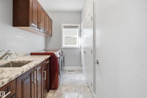Upper and lower wood cabinetry, solid surface countertop with undermount sink, and tiled flooring - 427 Windermere Road Nw, Edmonton, AB - Indoor