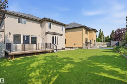 Expansive backyard featuring a manicured lawn, a raised deck with dark railings, and a privacy fence - 427 Windermere Road Nw, Edmonton, AB - Outdoor With Deck Patio Veranda With Exterior