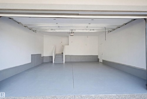 Expansive garage with painted concrete flooring, clean white walls, and a convenient interior access door - 427 Windermere Road Nw, Edmonton, AB - Indoor Photo Showing Garage