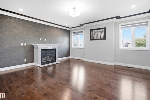 Hardwood flooring, gas fireplace with stone surround, recessed lighting, and crown molding - 427 Windermere Road Nw, Edmonton, AB - Indoor Photo Showing Living Room With Fireplace