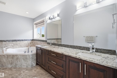 Dual vanity with granite countertops, rich wood-finish cabinetry, and undermount sinks - 427 Windermere Road Nw, Edmonton, AB - Indoor Photo Showing Bathroom