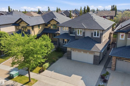 Two-story residence featuring a large driveway, attached garage, and stone accents - 427 Windermere Road Nw, Edmonton, AB - Outdoor With Facade