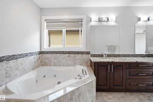 Corner soaking tub with tile surround, dual vanities with granite countertops, and dark wood cabinetry - 427 Windermere Road Nw, Edmonton, AB - Indoor Photo Showing Bathroom