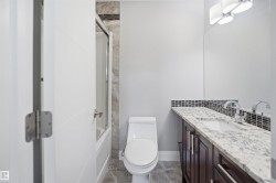 White flat panel door, full-size built-in bathtub with glass enclosure, white toilet, dark wood-finish vanity with drawer and cabinet storage, and a white countertop with an undermount sink - 