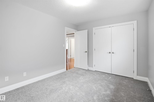 Gray wall paint with white trim, gray carpet flooring, white bi-fold closet doors, and white interior doors with satin nickel hardware - 427 Windermere Road Nw, Edmonton, AB - Indoor Photo Showing Other Room