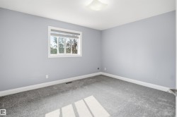 Recessed window with white trim, light gray walls, gray carpet flooring, and a white ceiling-mounted light fixture - 