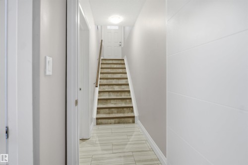 Tiled flooring leading to carpeted stairs with a wood handrail - 427 Windermere Road Nw, Edmonton, AB - Indoor Photo Showing Other Room